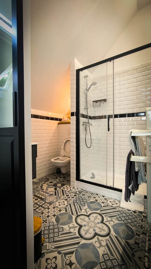 Salle de bain moderne au Clos du Buisson avec douche à cadre noir, carrelage blanc subway, sol à motifs et toilettes indépendantes