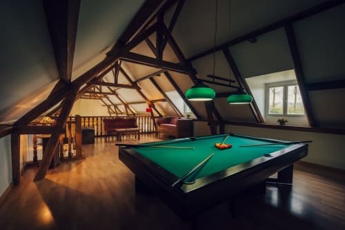 Salle de billard du Clos Céleste avec table de pool verte, poutres apparentes, lampes suspendues et parquet à Étretat.
