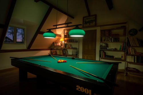 Pool table with green felt and bright pendant lights in Clos Céleste's game room, Ecrainville, France.