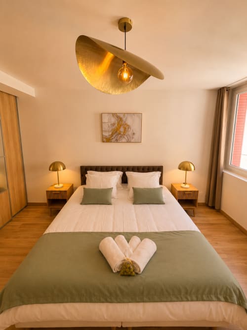 Luxury studio bedroom at Le Clos Androne hotel in Sisteron with modern brass pendant light, white bedding, and citadel view