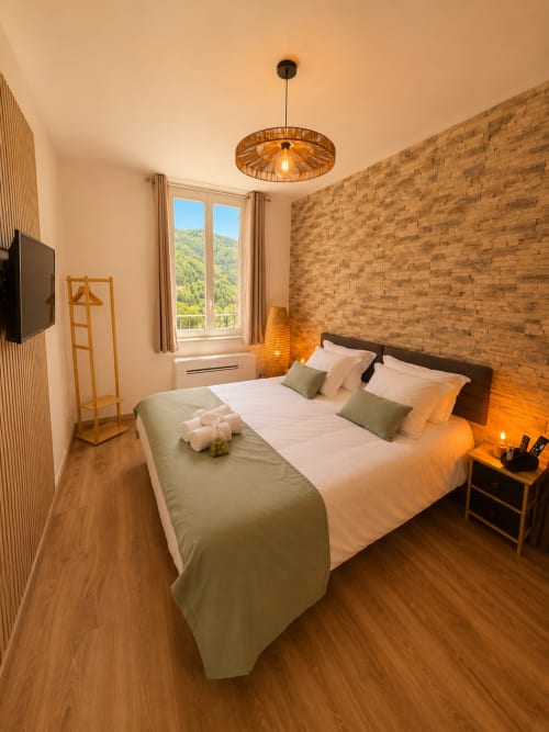 Cozy Studio Confort bedroom at Le Clos Androne, Sisteron with brick wall, mountain view, and warm ambiance
