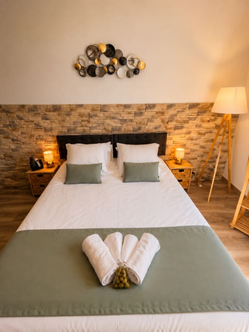 Cozy Studio Confort bedroom at Le Clos Androne with brick accent wall, wooden floors, and mountain views in Sisteron