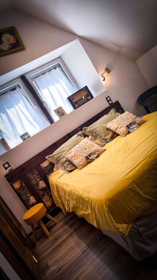 Chambre double lumineuse avec literie jaune, oreillers beige, vue sur le jardin et parquet à Le Clos du Buisson B&B
