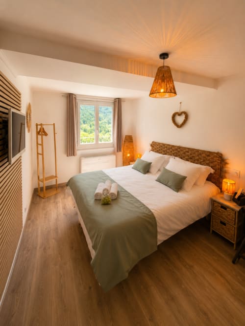 Modern studio bedroom at Le Clos Androne, Sisteron with mountain views, woven headboard, and warm lighting
