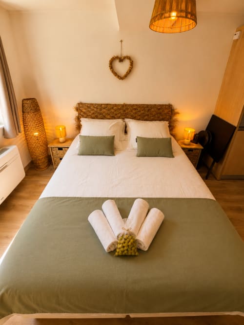 Cozy bedroom at Le Clos Androne hotel in Sisteron with wicker headboard, white linens, and mountain view decor