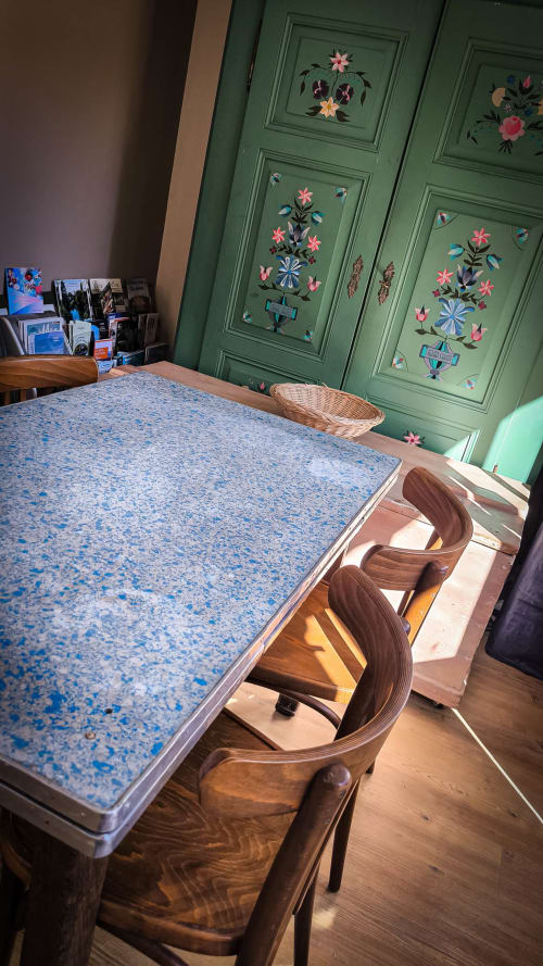 Salle à manger au Clos du Buisson avec table à taches bleues, chaises en bois et portes vertes ornées de peintures florales