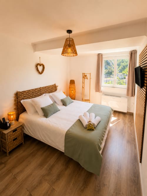 Cozy studio bedroom at Le Clos Androne in Sisteron with woven headboard, mountain views, and warm natural lighting