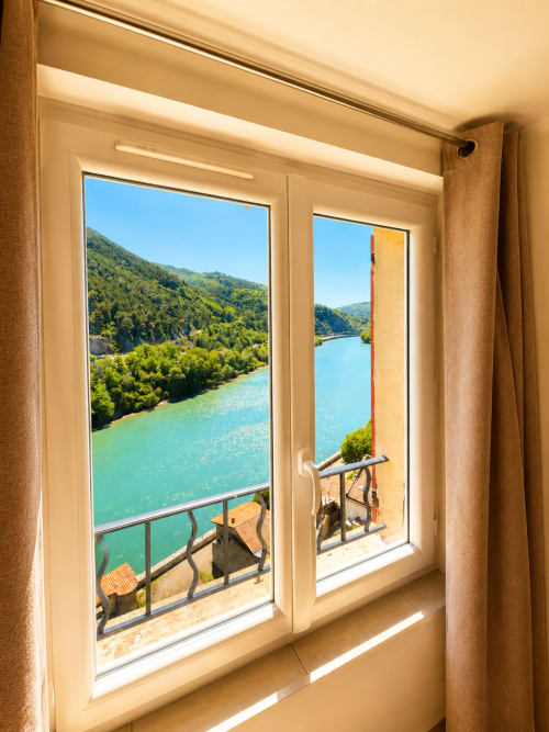 Studio window in Sisteron overlooks turquoise Durance river, green forested hillsides, and mountain landscape from Le Clos