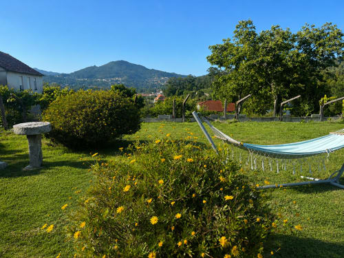 Vista del jardín de la cabaña Holibai en Gondomar con hamacas, flores amarillas y vistas a las montañas