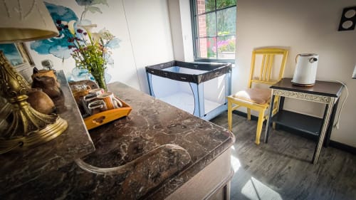 Chambre moderne au Clos du Buisson avec comptoir en marbre noir, chaise jaune, vue sur le jardin et équipements de cuisine
