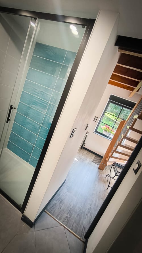 Salle de bain moderne avec douche en carrelage turquoise et porte vitrée encadrement noir à Le Clos du Buisson B&B, Saint Aubin sur Gaillon