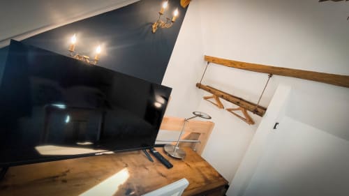 Chambre moderne au Clos du Buisson avec TV écran plat, bureau en bois et poutres rustiques sous plafond cathédrale