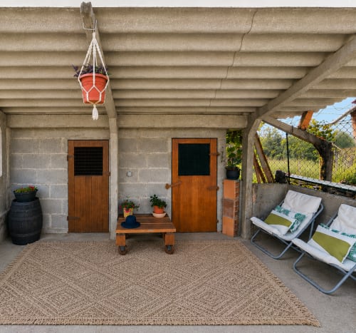 Patio de la casita Nova Anduriña en Holibai, Gondomar, con puertas de madera, macetero colgante, tumbonas y vistas al jardín
