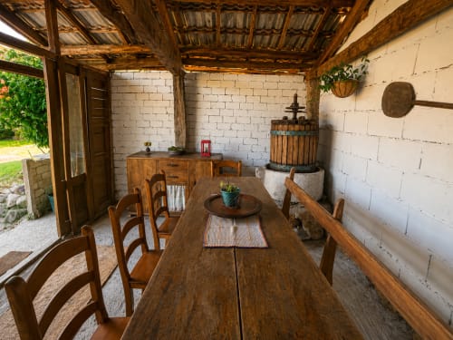 Comedor rústico con mesa de madera, sillas y techo de vigas en la casita Nova Anduriña de Holibai, Gondomar