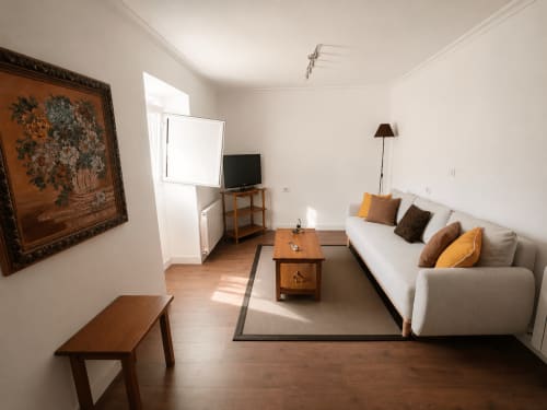 Luminosa sala de estar en la cabaña Nova Anduriña de Holibai, Gondomar, con sofá crema, muebles de madera y vistas al jardín