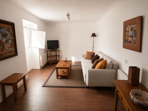Acogedora sala de estar en la cabaña Nova Anduriña de Holibai, Gondomar con sofá beige, muebles de madera y TV