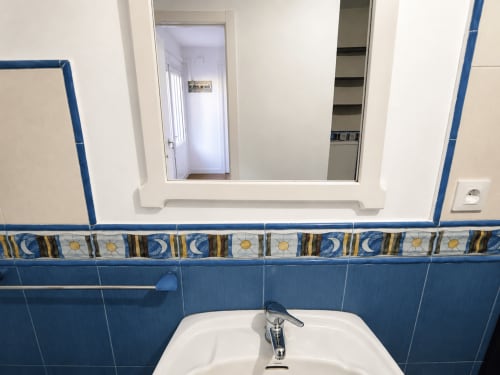 Lavabo de baño con paredes de azulejos azules y franja decorativa con motivos de sol y luna en la cabaña Holibai, Gondomar