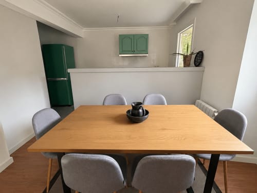 Comedor de la casita Nova Anduriña en Holibai, Gondomar con mesa de madera, sillas grises, nevera verde y cocina