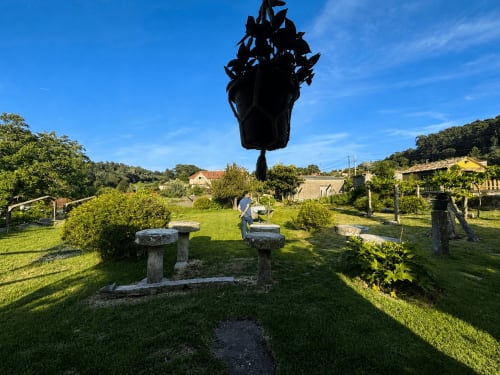 Jardín de la casa Holibai en Gondomar con zona de descanso en piedra, césped exuberante y árboles bajo cielo azul