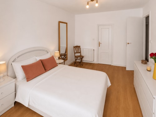 Amplia habitación de la casa rural Nova Anduriña en Holibai con cama blanca, suelo de madera y vistas al jardín en Gondomar