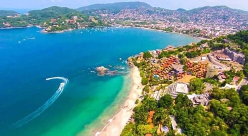 Vue aérienne de l'hôtel Ensueño De Fuga surplombant une baie turquoise et plage de sable à Zihuatanejo, Mexique
