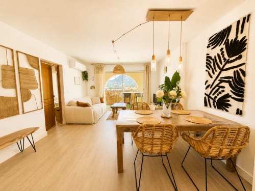 Lumineux appartement ouvert à L'Île-Rousse, table à manger, chaises en rotin, meubles en bois, vue sur les montagnes