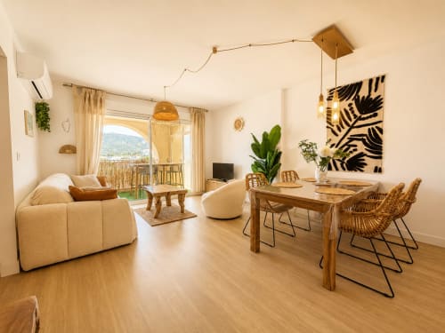 Appartement moderne à L'Île-Rousse avec séjour ouvert, vue montagne, chaises en rotin et décoration contemporaine
