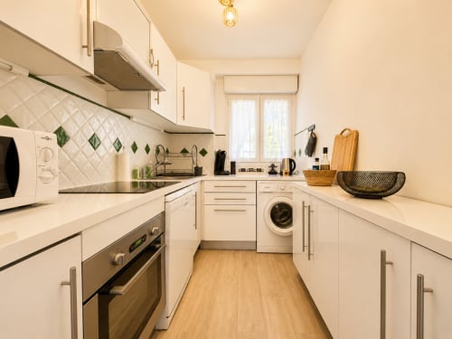 Cuisine moderne blanche avec électroménagers en acier inoxydable, lave-linge et comptoirs en bois à L'Île-Rousse