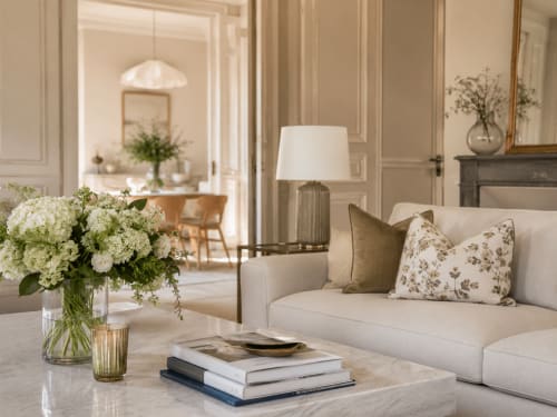 Elegant living room at ARLOÉ hotel in La Rochelle with cream sofa, white hydrangeas, marble table, and refined neutral décor