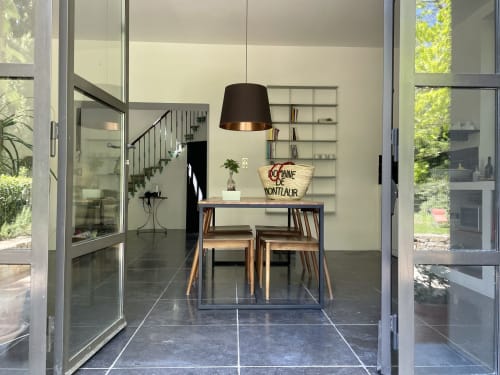 Intérieur de cottage moderne au Domaine de Montlaur avec table de salle à manger, lampe suspendue et portes vitrées ouvertes sur le jardin