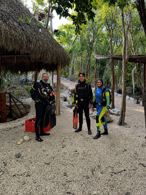 Tres buzos en trajes de neopreno en Hotel Boutique Cenote Secreto Maya en Valladolid, Yucatán, México