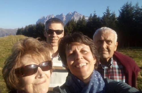 Famille souriante devant l'Hôtel Les Triolets à Châtel avec les Alpes et forêts en arrière-plan