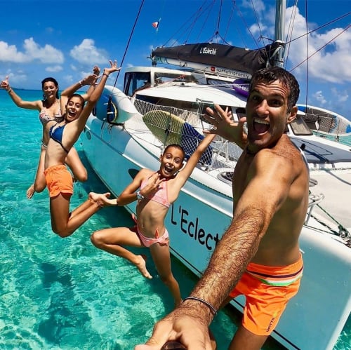 Family enjoying tropical waters at Moorea Tiki Lodge, jumping off catamaran in turquoise lagoon
