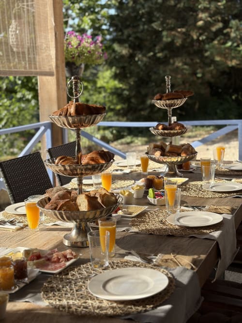 Elegant outdoor breakfast spread at La Maison Du Chevalier in Marat, France, with tiered pastry stands and fresh juice.