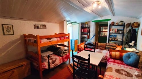 Chambre Marie-Ange at Le Portel des Arnaud with bunk beds, red bedding, shelving, and garden view in Durfort, France