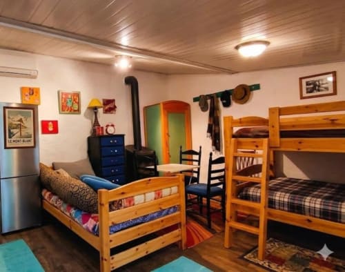 Cozy multi-bed room at Le Portel des Arnaud with wooden bunk beds, blue dresser, and rustic charm in Durfort, France
