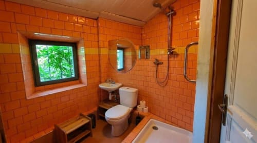 Modern bathroom with vibrant orange tile walls, walk-in shower, and garden view window at Le Portel des Arnaud B&B