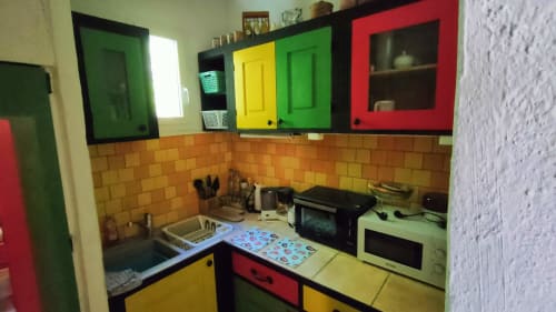 Colorful kitchen with yellow and green cabinets, orange tile backsplash at Le Portel des Arnaud B&B