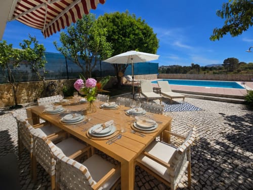 Luxury villa outdoor dining area with pool and blue umbrella in Sesimbra, Portugal
