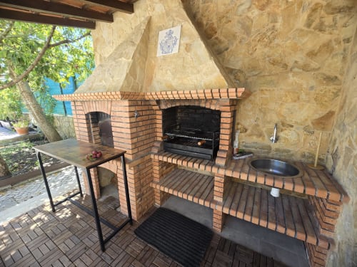 Outdoor kitchen area at Casa Forever Young villa in Sesimbra with brick fireplace, grill, and dining setup
