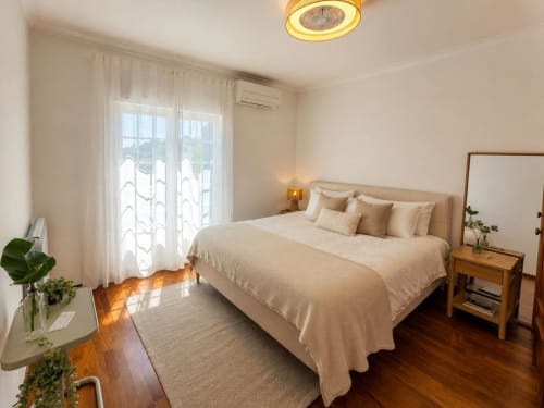 Bright modern bedroom in Casa Forever Young villa, Sesimbra with cream bedding, wooden nightstand, garden view, and ceiling