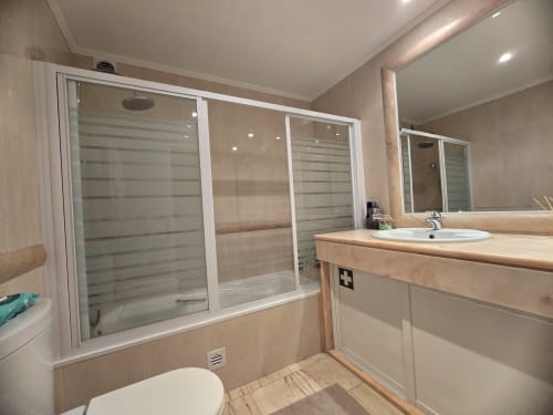 Modern bathroom in Sesimbra villa with walk-in shower, vanity sink, toilet, and heated lighting