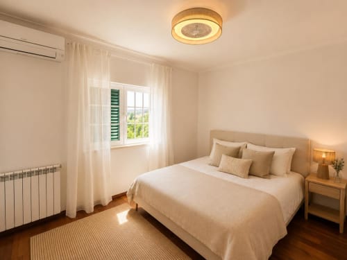 Bright bedroom at Casa Forever Young villa in Sesimbra with queen bed, garden views, and modern ceiling fan