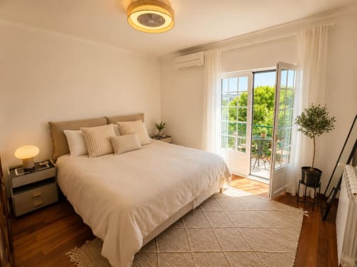 Bright bedroom in Sesimbra villa with queen bed, garden view balcony, wooden floors, and modern amenities
