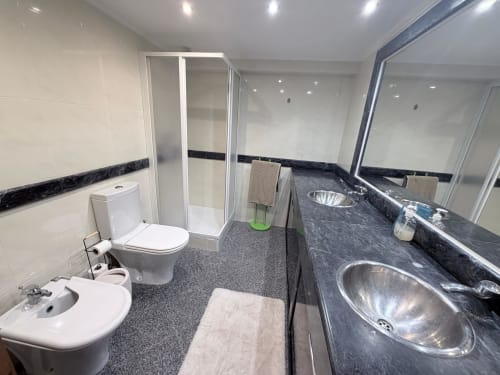 Modern bathroom in Casa Forever Young villa at Sesimbra Sun Sea with dual sinks, shower enclosure, toilet, and dark marble