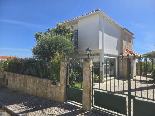 Casa Forever Young villa in Sesimbra with white-washed walls, stone exterior, gated entrance, and lush garden views under