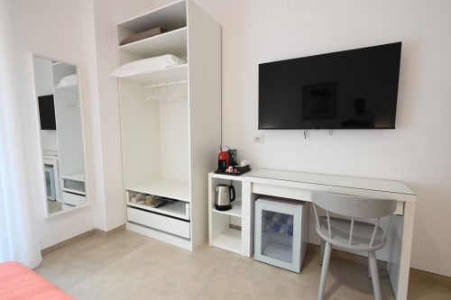 Chambre moderne de l'hôtel Melo 48 Bari avec télévision écran plat, bureau, penderie et minibar