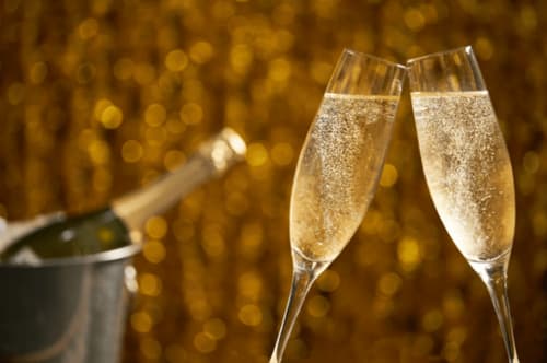 Two champagne flutes toasting with bottle in ice bucket at Clos Céleste, Etretat