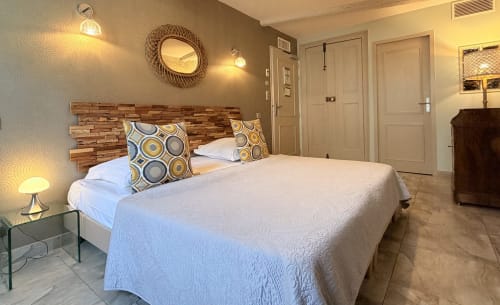 Modernes Hotelzimmer im Hôtel La Suite in Villeneuve-lès-Avignon mit Holzbettrahmen, weißer Bettwäsche und warmem Licht