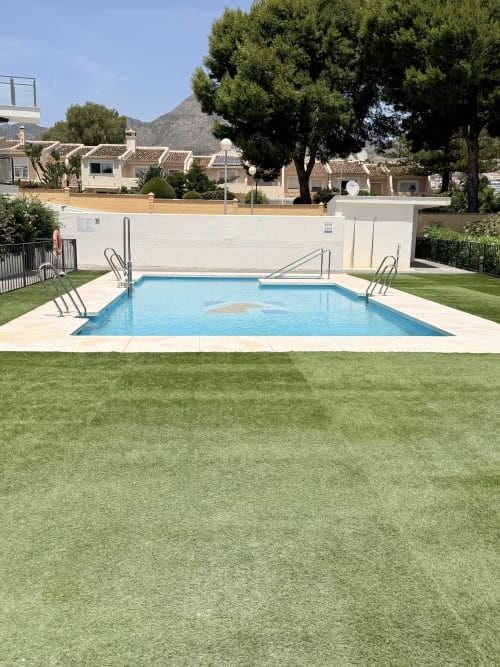 Casita familiar en Benalmádena con piscina, jardín impecable, paredes blancas, tumbonas y vistas a las montañas
